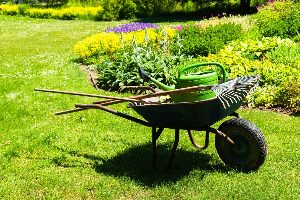 Un jardinier met la brouette avec les outils de jardinage dans les jardins
