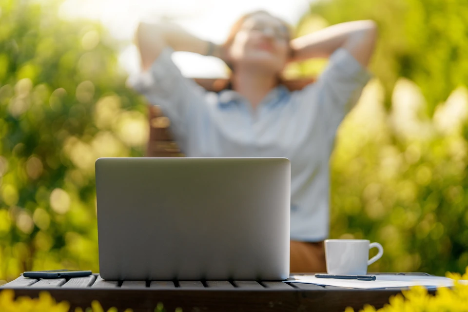 Femme souriante taillant une haie avec un taille-haie électrique dans un jardin résidentiel
